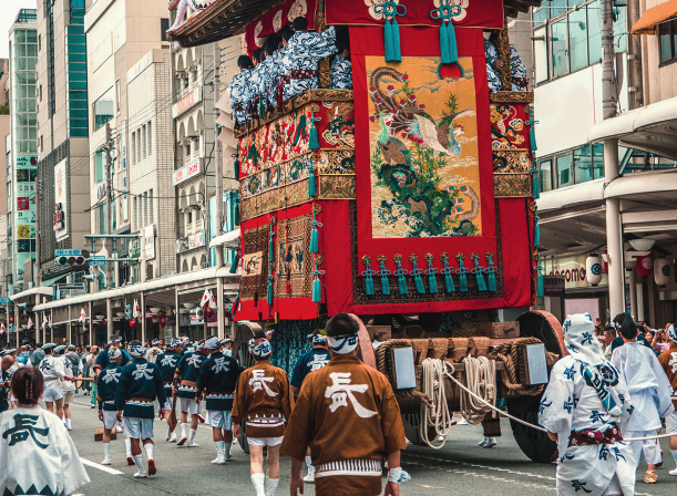 A Sakuraco Japanese Snack Box beside an image of a traditional Japanese festival (matsuri).