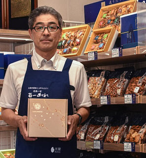 Japanese snack maker Kikuichi Arare President Hajime Watanabe holding a Sakuraco Japanese snack box.
